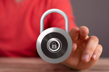 Close-up of a hand holding a silver padlock representing concepts of security, protection, and...