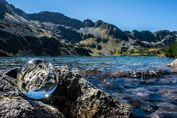 a glass ball against the background of a lake in a valley of 5 ponds in the Polish Tatra Mountains