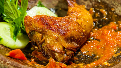 A deliciously cooked chicken dish smothered in a vibrant red sauce, served with fresh cucumber slices on the side