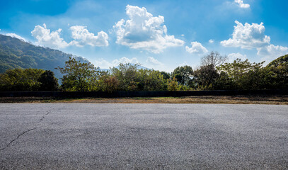 Empty asphalt road ground and green trees with mountain landscape under blue sky