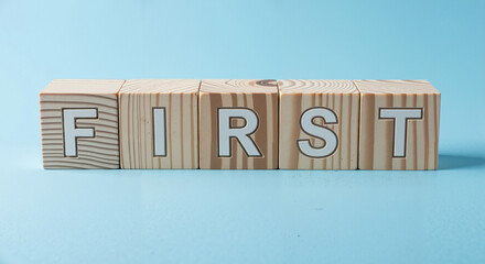 Wooden blocks spelling the word "FIRST" on a blue background