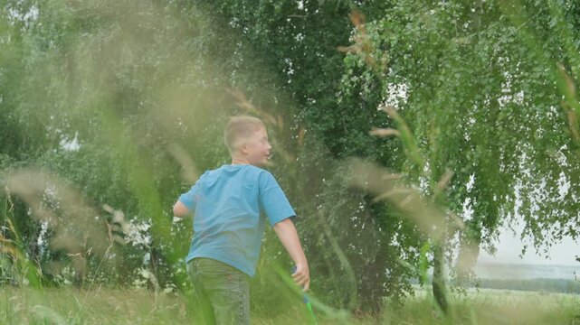 white boy and girl playing outdoors, big brother launching toy plane while little sister watches amid tall grass, birch tree backdrop, soft sunlight, summer breeze, candid motion and joyful laughter,