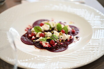 sliced beetroot appetizer on a white plate, goat cheese and fresh herbs, healthy vegetarian food, close-up view, elegant food presentation,