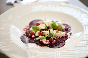 sliced beetroot appetizer on a white plate, goat cheese and fresh herbs, healthy vegetarian food, close-up view, elegant food presentation,