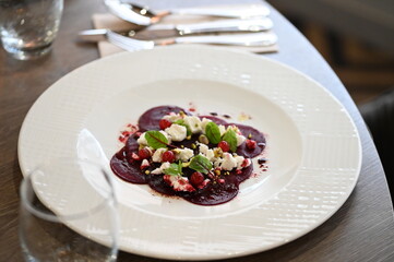 beetroot carpaccio served on a white plate, close-up of modern vegetarian dish in a restaurant, elegant food presentation, healthy gourmet cuisine,