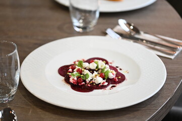 sliced beetroot appetizer on a white plate, goat cheese and fresh herbs, healthy vegetarian food, close-up view, elegant food presentation,