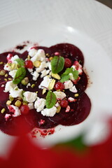 sliced beetroot appetizer on a white plate, goat cheese and fresh herbs, healthy vegetarian food, close-up view, elegant food presentation,