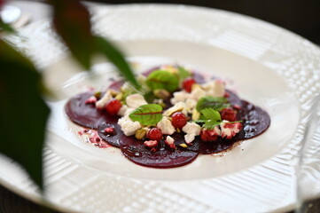 sliced beetroot appetizer on a white plate, goat cheese and fresh herbs, healthy vegetarian food, close-up view, elegant food presentation,