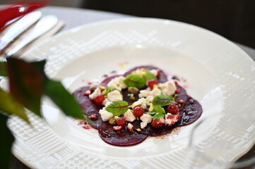 sliced beetroot appetizer on a white plate, goat cheese and fresh herbs, healthy vegetarian food, close-up view, elegant food presentation,