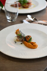 scallops with pumpkin puree, gourmet appetizer, served on a white plate in a restaurant, close-up food photography, elegant fine dining presentation,