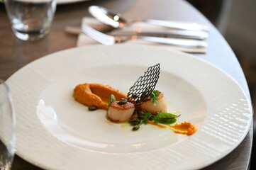 scallops with pumpkin puree, gourmet appetizer, served on a white plate in a restaurant, close-up food photography, elegant fine dining presentation,