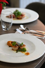 scallops with pumpkin puree, gourmet appetizer, served on a white plate in a restaurant, close-up food photography, elegant fine dining presentation,
