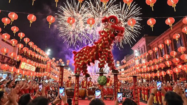 Nighttime scene of a large crowd watching a fire-breathing dragon dance performance with fireworks and lanterns in a city street at night.