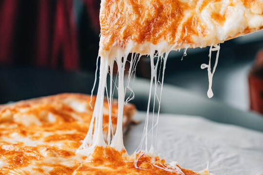 Pizza or Imeretian khachapuri slice lifting with hot melted cheese creating a stretchy and tempting pull