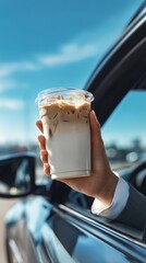 A hand holds a refreshing iced coffee drink. with a clear blue sky, a car, and nature blur in the background. Capturing the essence of a simple joy on a sunny day.