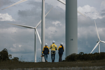 Team of wind turbine technicians wearing safety gear walking confidently at wind farm, symbolizing teamwork, clean energy industry, professional field operations.