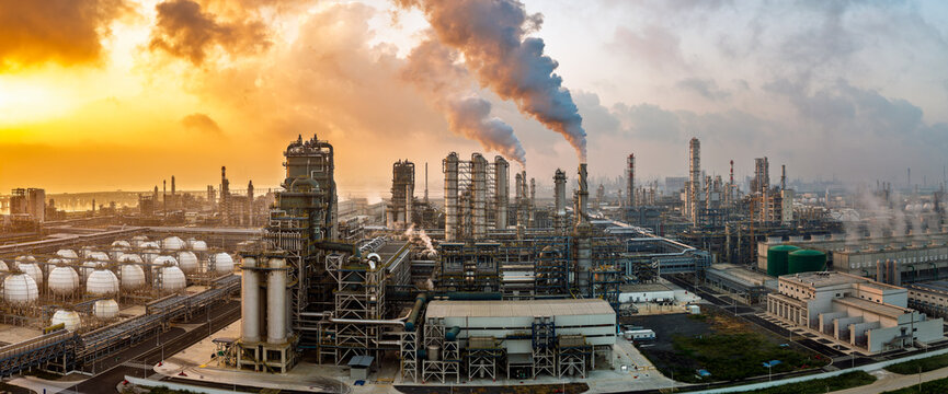 Aerial view of an oil refinery and chemical plant with smoking chimneys at sunset