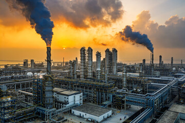 Aerial view of an oil refinery and chemical plant with smoking chimneys at sunset