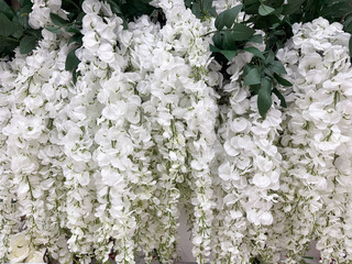 Cascading white artificial flowers with green leaves create a lush decorative floral wall display