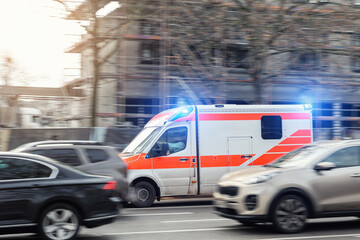 Ambulance flash emergency lights driving fast busy city traffic jam motion blur among cars urban road. Urgent medical response scene shows rescue transport public safety service rapid European city