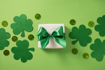 St Patricks day and March 17 concept with gift and clover leaves on green background. View from above.