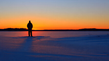 Obraz premium Man Silhouette at Sunset on Frozen Lake