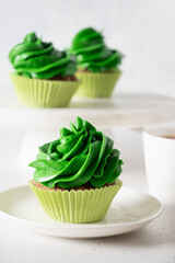 Homemade chocolate cupcake with green whipped cream on white background. St. Patrick's Day festive food.