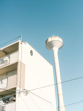 Minimal Japanese Apartment Building and Water Tower Under Clear Blue Sky
