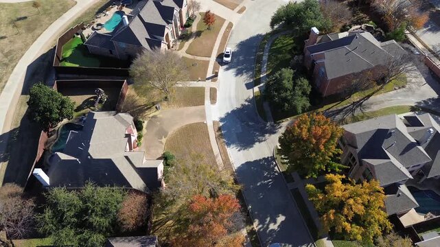Curving streets follows densely packed Coppell upscale suburban homes pitched roofs, fenced yards, pools. Autumn foliage mixes green, yellow, brown highlights fall to winter transition in Texas