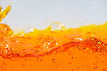 Vibrant orange liquid splashing, creating dynamic waves and droplets. High-speed abstract action shot perfect for beverage, juice, soda, or energy drink advertising and refreshment promotion