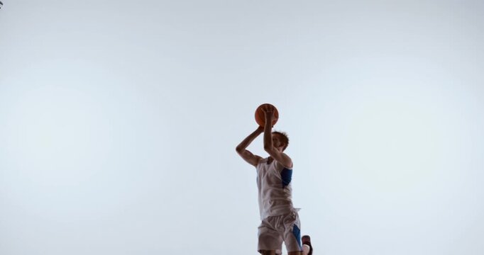 Basketball player reaching upward for ball in active two arm motion. Concept of skill demonstration, team training visuals, fitness improvement, and motion technique reference.