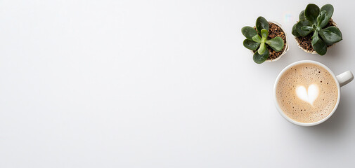 Flat lay of cup of coffee with heart latte art and two small plants on white background symbolizing calm lifestyle, freshness, and creativity.