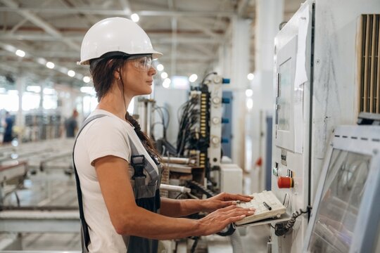 Side view of machine operator. Woman is in the window making factory