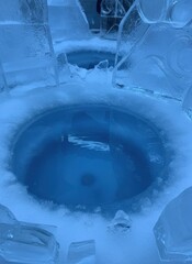 Intricate Ice Sculptures With Circular Blue Water Features And Snow Surrounding At Night With Blue Lighting