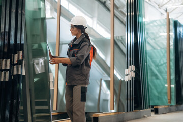 Wireless device, laptop in hands, walking. Woman is in the window making factory