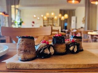 Traditional Georgian eggplant rolls filled with walnut paste, herbs, and spices, known as badrijani nigvzit, garnished with fresh pomegranate seeds and served as a classic cold appetizer