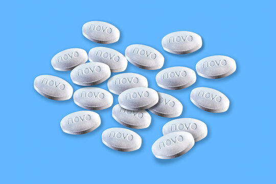 Stack of pills from Novo Nordisk lies on a blue background. Copenhagen, Denmark - December 23, 2025.