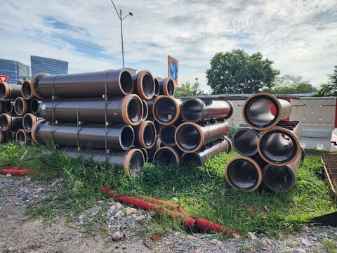 Stacks of vitrified clay pipes (VCP) stored at a construction site, prepared for underground drainage and sewerage installation