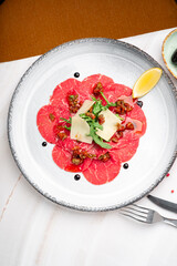 Classic Italian beef carpaccio with thinly sliced raw fillet, parmesan shavings, arugula, capers, and balsamic glaze. Elegant meat starter, gourmet antipasto, premium Italian cuisine