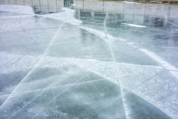 Scratched frozen ice surface with reflections in pale winter light