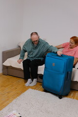 Senior European tourists couple packing clothing and travel essentials for awaited vacation, preparing for trip. High quality photo
