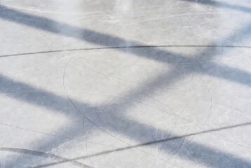 Scratched ice rink with shadows in winter sunlight