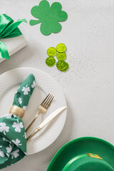 St Patricks day flat lay with green shamrock symbol and lucky coins on light background. Vertical format. Irish holiday decoration concept.
