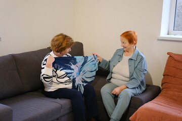 Two mature women friends mother and daughter using smartphone while sitting on sunny terrace of country house. High quality photo
