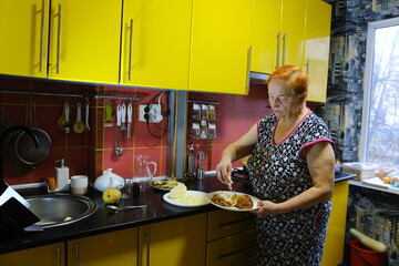 Senior woman cooking food on the stove in kitchen. High quality photo