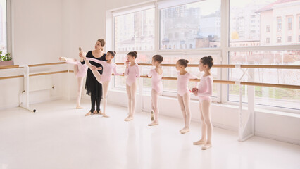 Young ballet dancers standing at barre awaiting individual instruction. Concept of classroom organization, turn based learning model, attention management, structured teaching process.