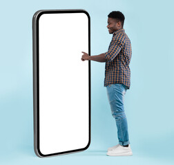 Side View Of Black Guy Using Big Cellphone With Blank White Screen Touching Huge Display Panel With...