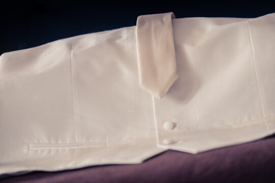 Close-up of a white waistcoat and tie on a sofa
