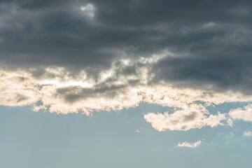 Dramatic stormy sky with dark gray, textured clouds, few light blue breaks, suggesting sunlight Cool tones prevail, with a subtle contrast from the light blue breaks Realistic style capturing depth