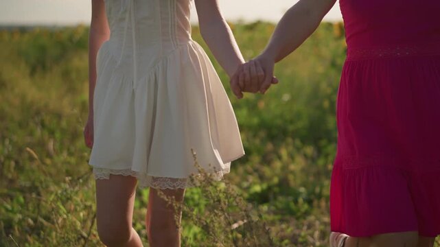 two asian women walking through field hands joined as they stride through tall grass, skirts swaying, golden light, playful steps and laughter, carefree summer mood and cinematic natural lifestyle